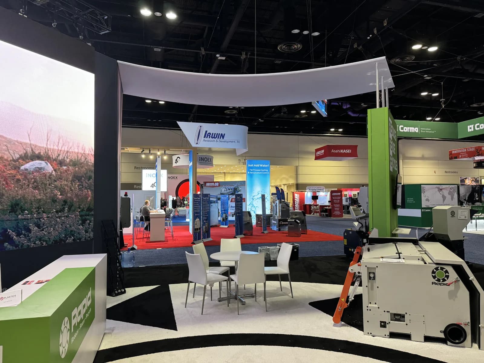 Curved black-and-white exhibit structure surrounding demonstration equipment and seating.